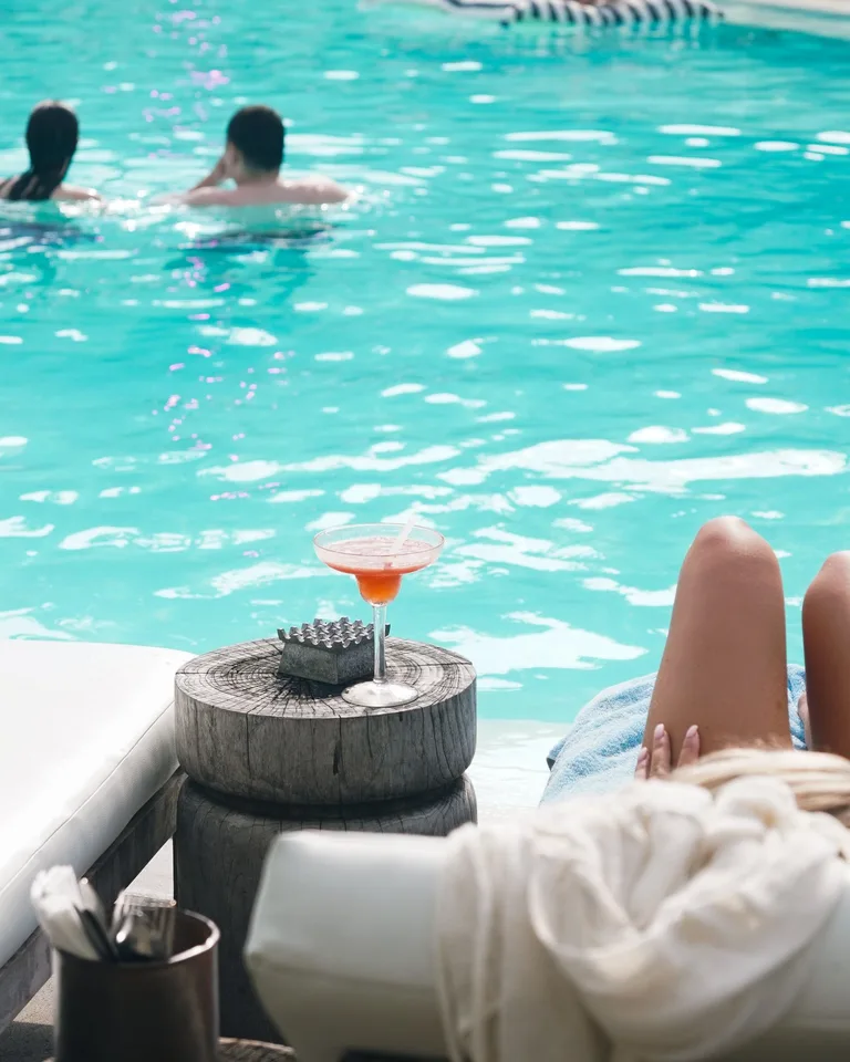Serene poolside scene with a cocktail, swimmers and a sunbather