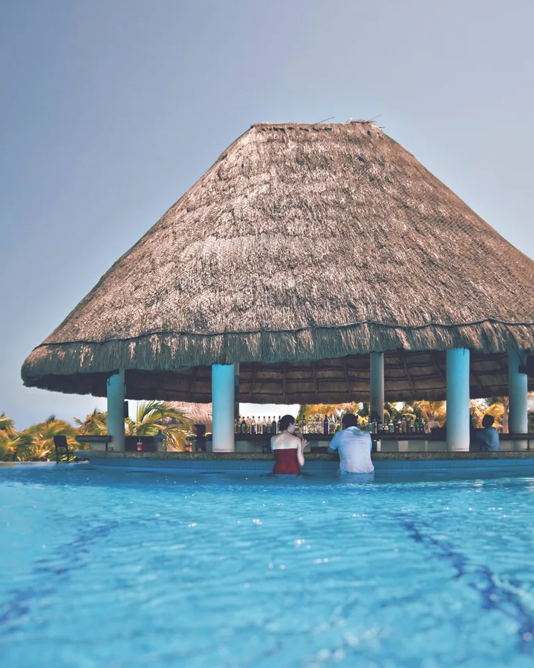 Serene poolside bar with a thatched roof at a lush resort