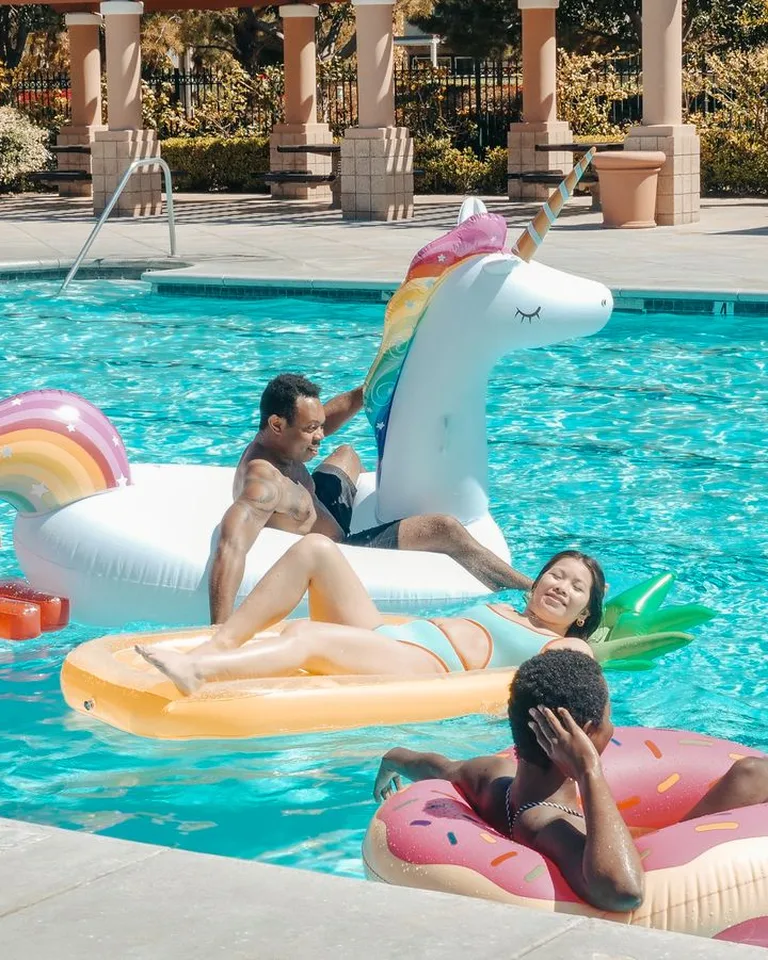 Group enjoying a summer pool party with colorful inflatable unicorn floats