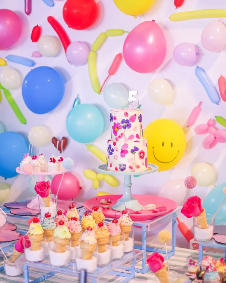 Colorful birthday dessert table with balloons and cake in a festive setting