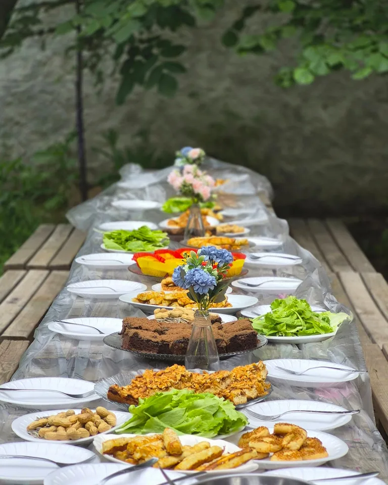 Long outdoor table set with an array of fresh dishes for a summer gathering