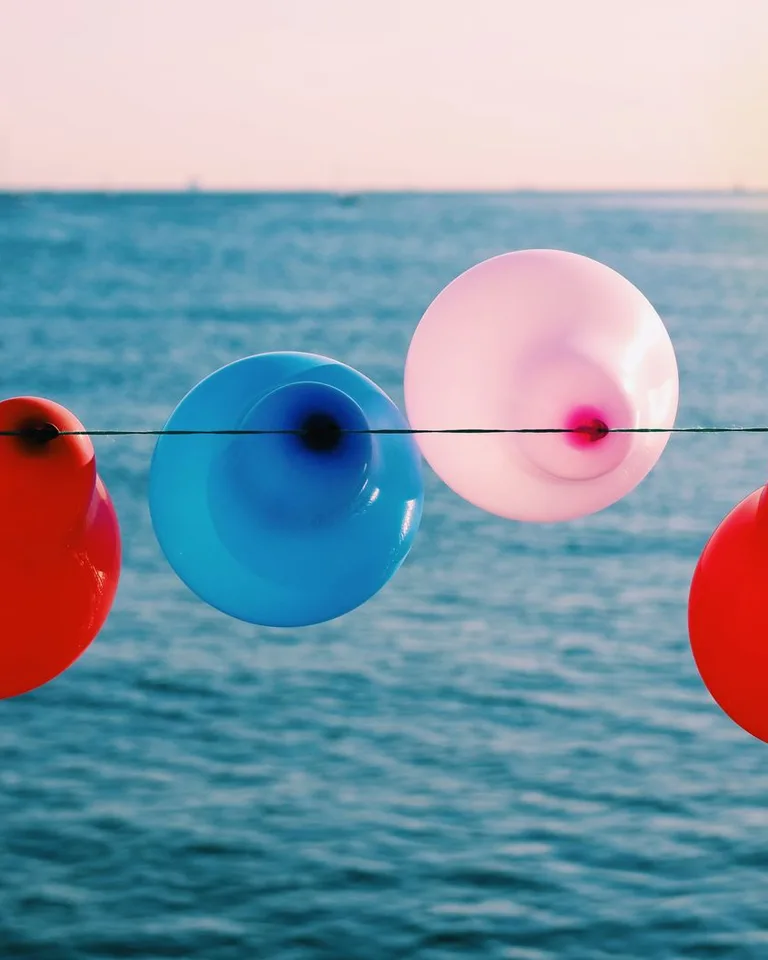 Colorful balloons hanging on a string at sunset by the sea
