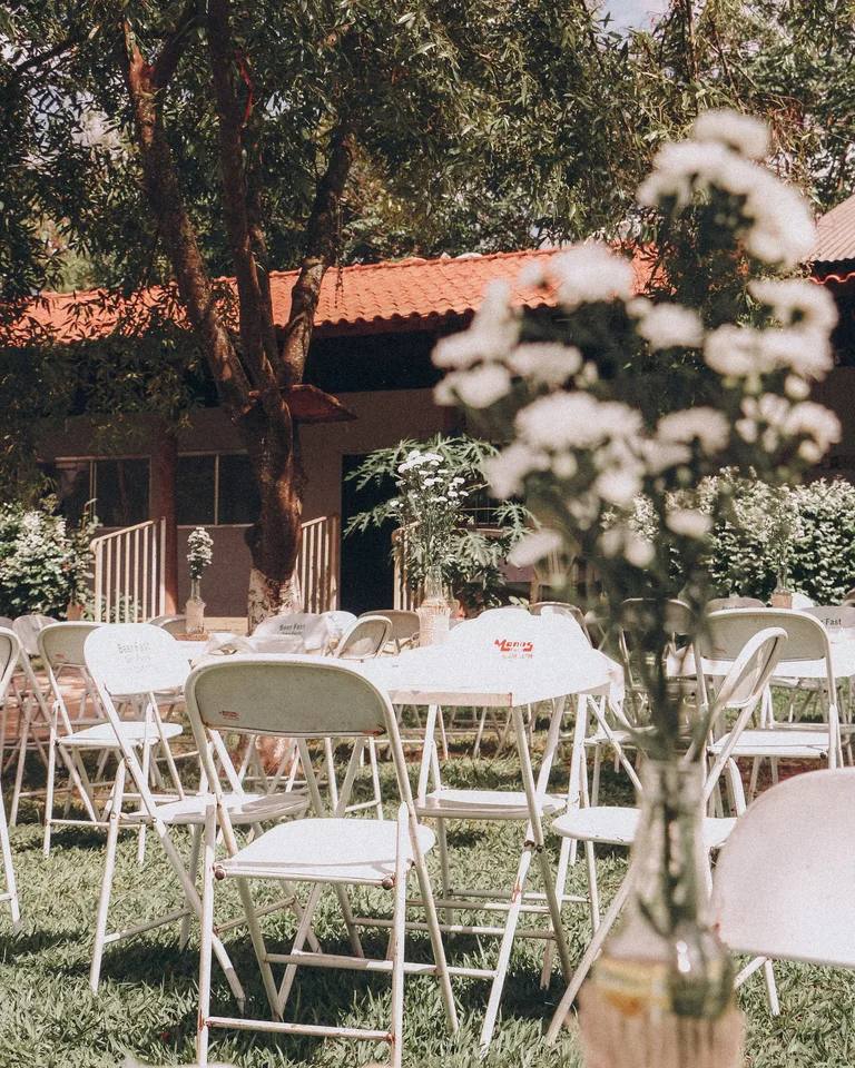 Sunny garden event setup with white chairs and floral arrangements