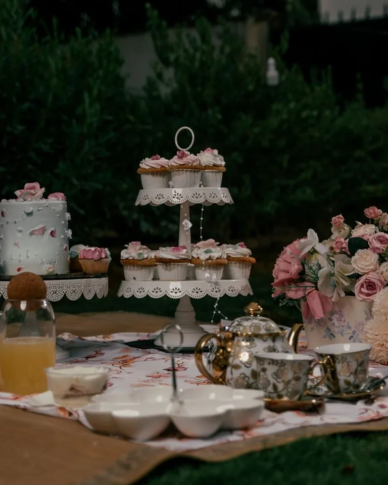 Charming outdoor tea party with floral decor, cupcakes and a vintage tea set