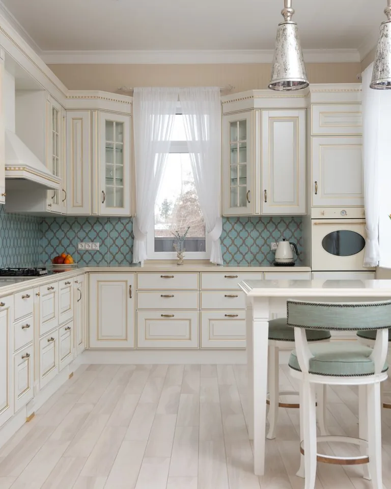 Bright summer kitchen with white cabinets and a wooden table by a sunny window