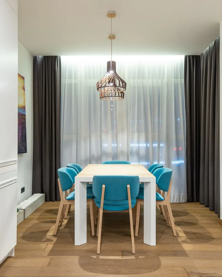 Kitchen table with colorful chairs by a curtained window