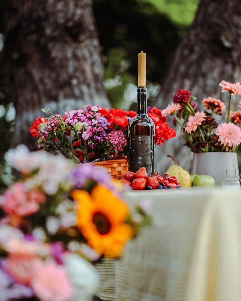 Colorful floral arrangement and wine bottle on a table outdoors