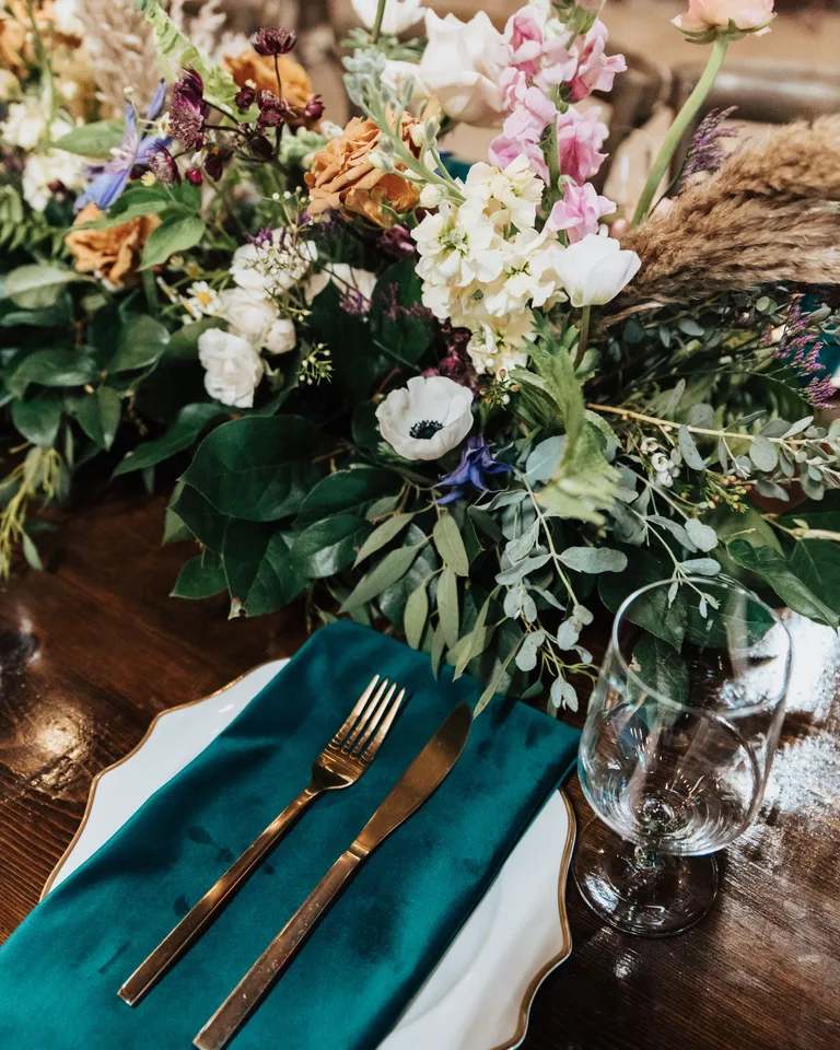 Charming table setting with a vibrant floral centerpiece and teal napkin