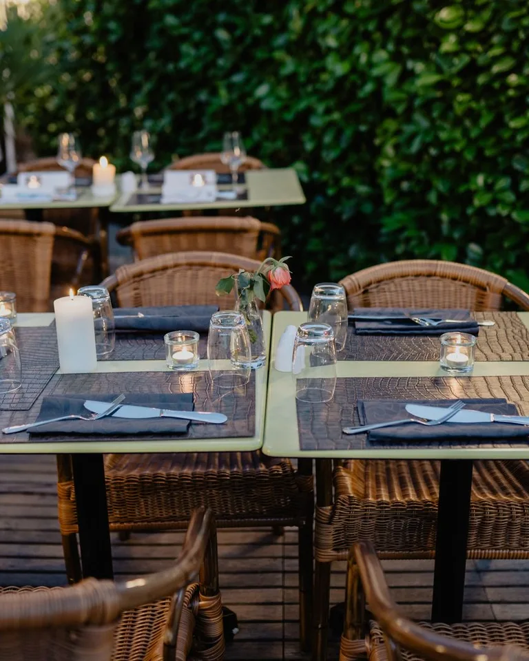 Intimate outdoor dining setting with wicker chairs and candlelit tables on a terrace